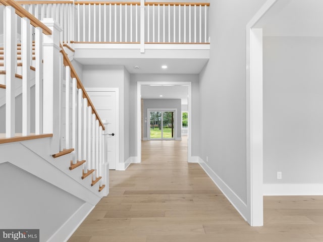 foyer entrance with light wood finished floors, baseboards, and stairway