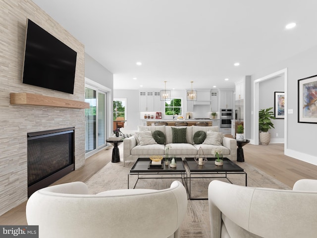 living area featuring recessed lighting, light wood finished floors, a large fireplace, and baseboards