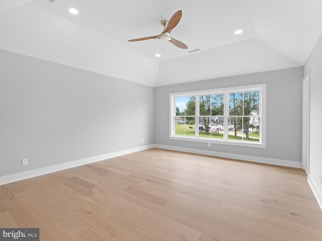 spare room featuring light wood-type flooring, baseboards, and lofted ceiling