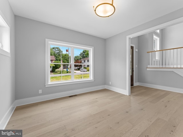unfurnished room featuring light wood-style floors, baseboards, and visible vents