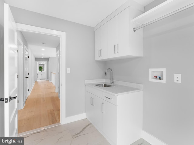 laundry area with hookup for a washing machine, marble finish floor, a sink, baseboards, and cabinet space