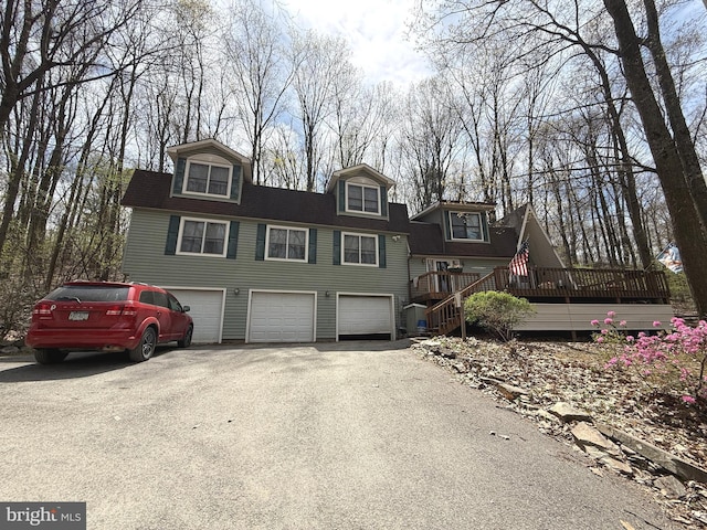 view of front facade featuring a garage, a wooden deck, and driveway