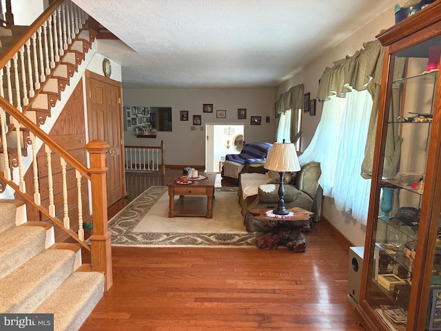 living area with stairs, baseboards, and wood finished floors