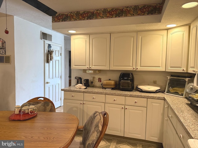 kitchen featuring visible vents, light countertops, and white cabinets
