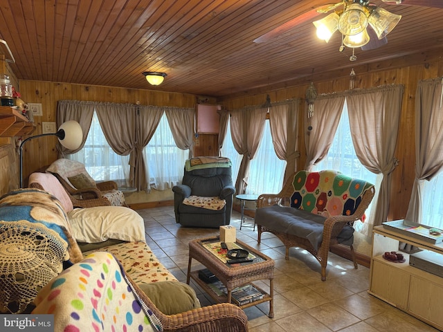 living room with wooden walls, a ceiling fan, light tile patterned floors, and wood ceiling