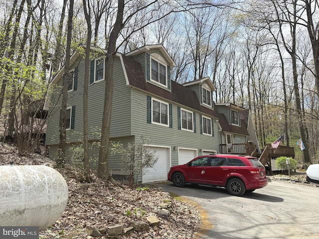 view of property exterior with a garage, a shingled roof, and driveway