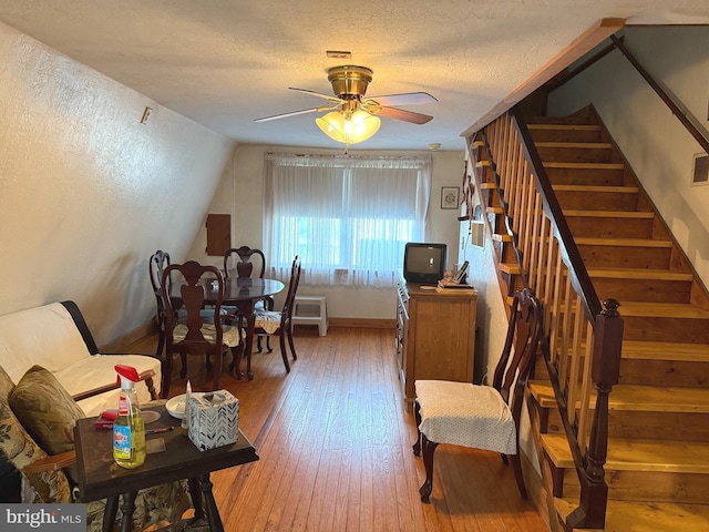 interior space with wood-type flooring, a textured ceiling, a ceiling fan, baseboards, and stairway