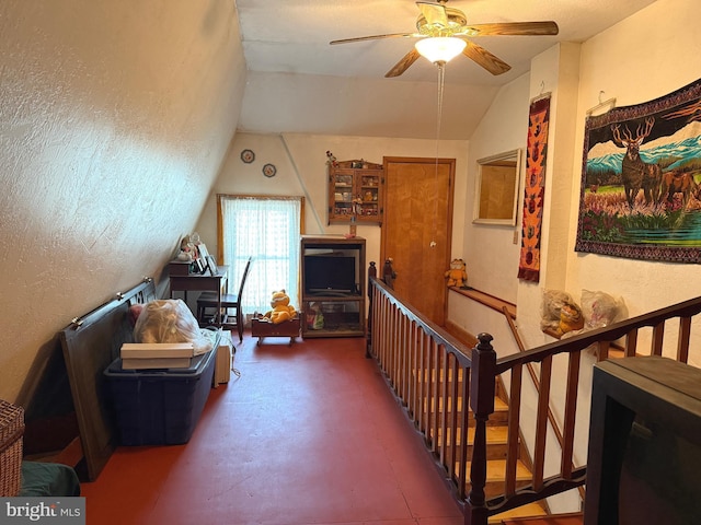living area featuring ceiling fan, lofted ceiling, finished concrete floors, and an upstairs landing
