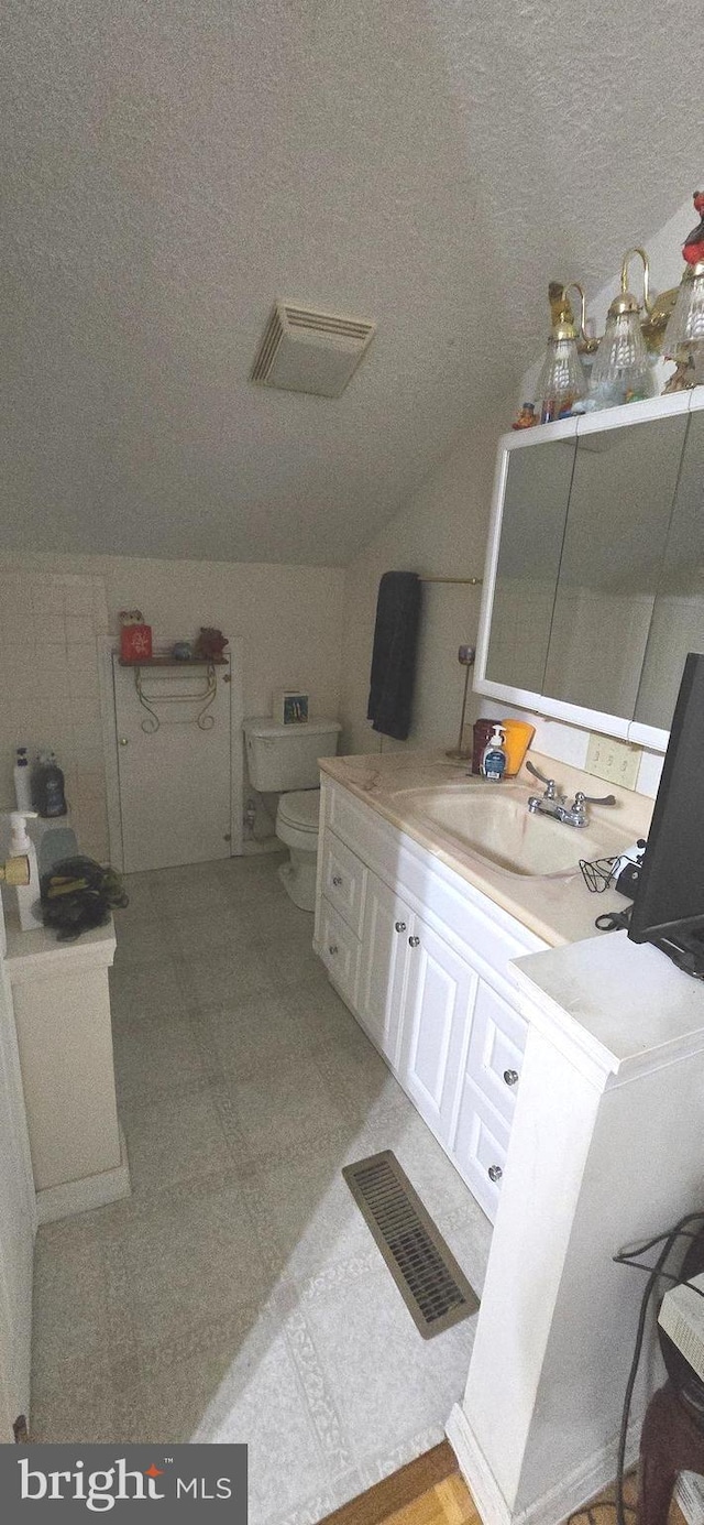 bathroom featuring toilet, visible vents, lofted ceiling, and vanity