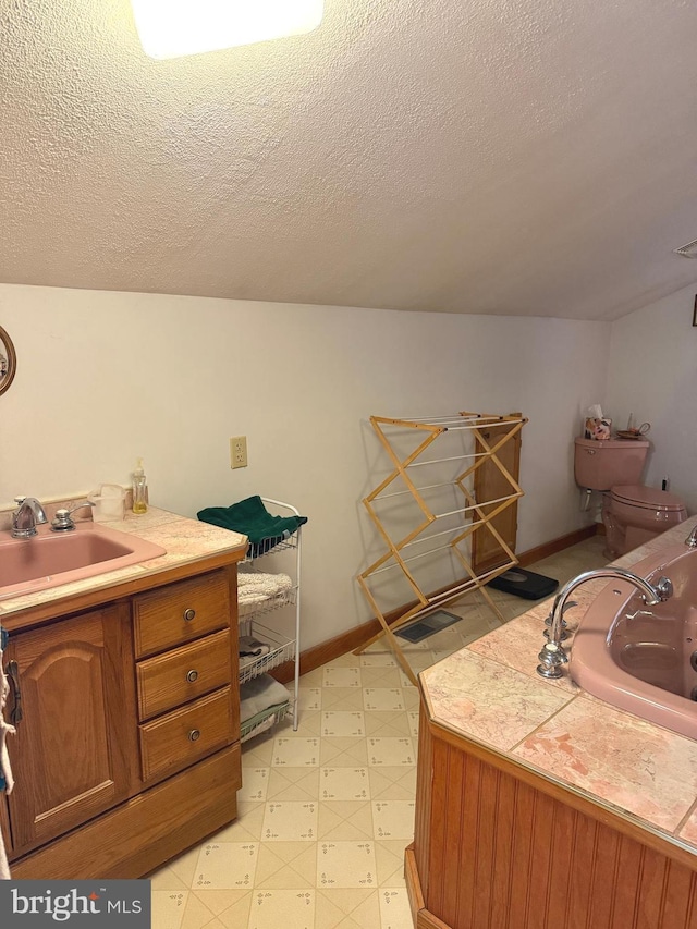 bathroom featuring vanity, toilet, baseboards, a textured ceiling, and tile patterned floors