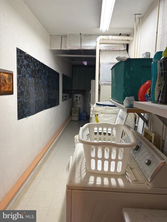 interior space featuring separate washer and dryer, laundry area, a textured wall, and tile patterned floors