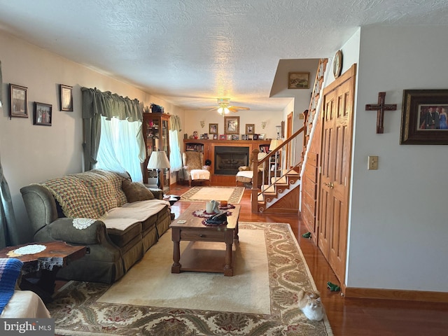 living area featuring a textured ceiling, wood finished floors, stairway, and a fireplace