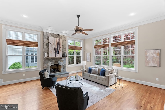 living area featuring baseboards, ornamental molding, a fireplace, and ceiling fan