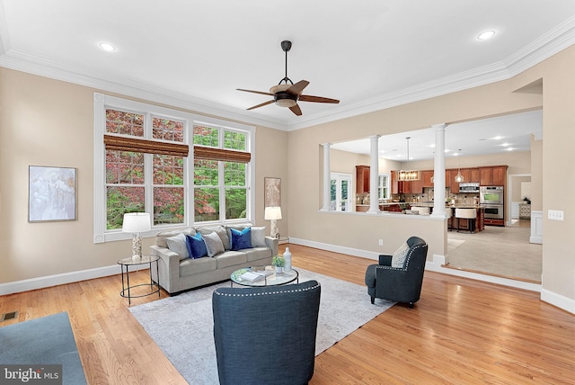 living area featuring baseboards, ornamental molding, light wood finished floors, and ceiling fan