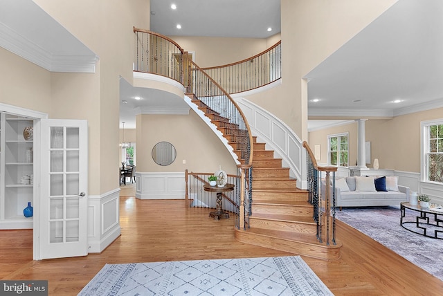 entryway featuring crown molding, a high ceiling, ornate columns, and stairs