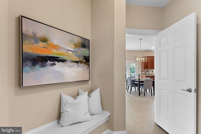 hallway featuring light tile patterned floors, baseboards, and a chandelier