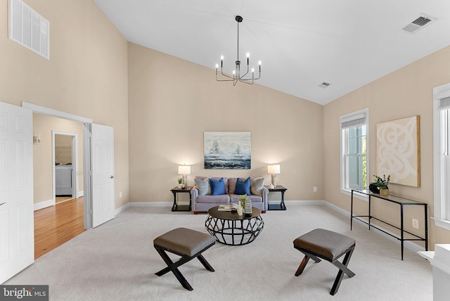 sitting room featuring visible vents, washer / dryer, high vaulted ceiling, carpet flooring, and a notable chandelier