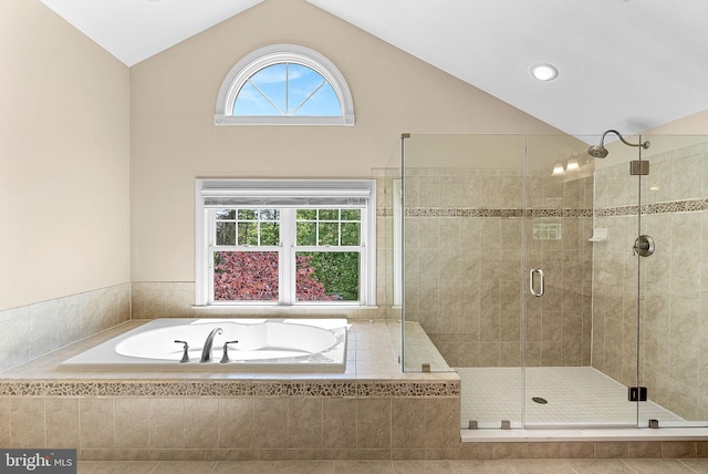 bathroom with vaulted ceiling, a bath, and a stall shower