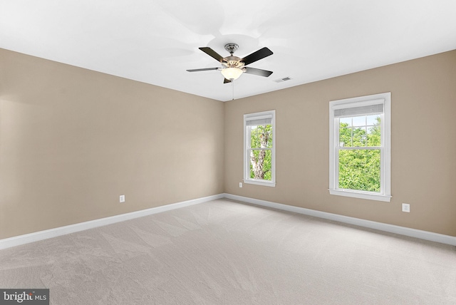 unfurnished room featuring baseboards, visible vents, a ceiling fan, and light colored carpet