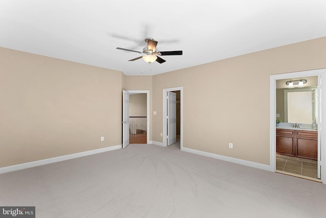 unfurnished bedroom with baseboards, a sink, a spacious closet, and light carpet