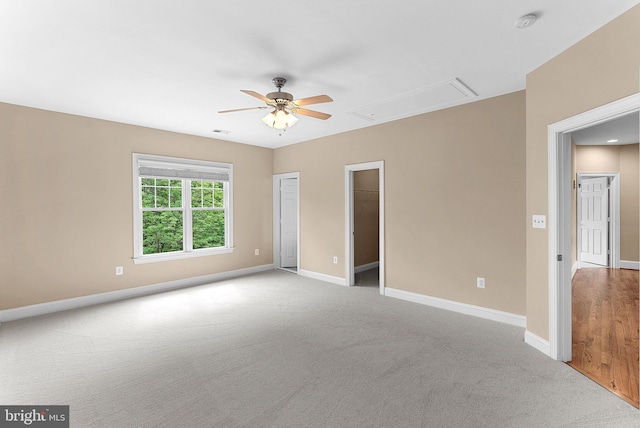 carpeted empty room with baseboards, a ceiling fan, attic access, and visible vents