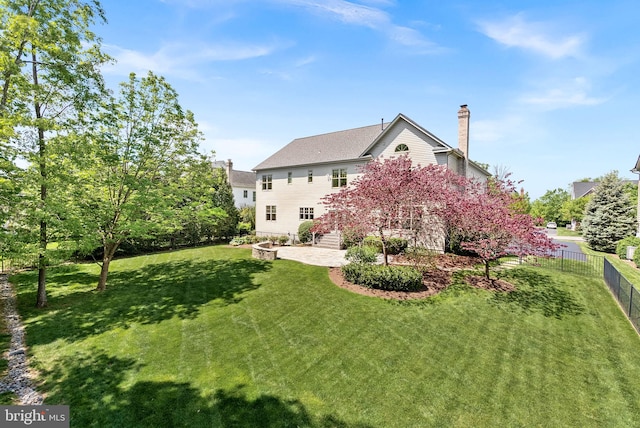 rear view of property featuring a lawn, fence, a patio, and a chimney