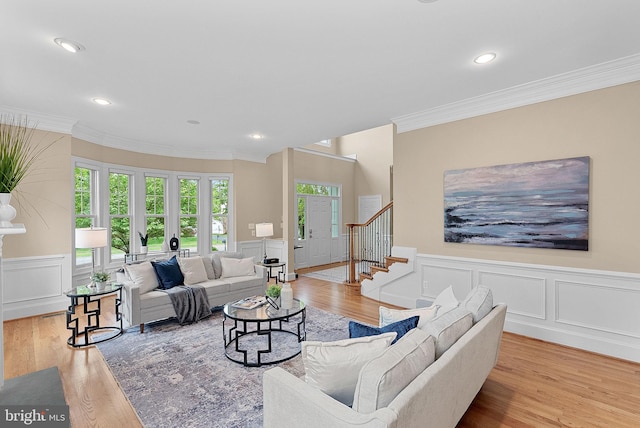living room featuring crown molding, a decorative wall, a wainscoted wall, stairs, and wood finished floors