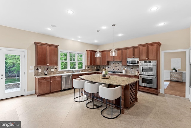 kitchen with a kitchen island, light stone countertops, a breakfast bar area, backsplash, and stainless steel appliances