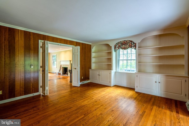 1428 Center Rd, Lancaster, PA 17603 - spare room featuring light wood-style flooring, crown molding, built in features, a fireplace, and wooden walls