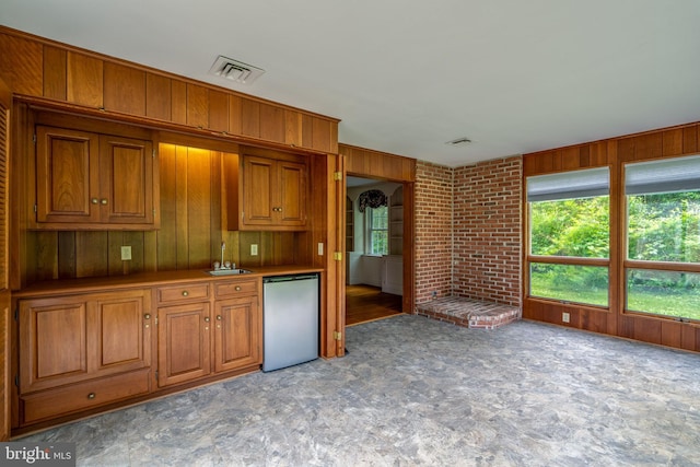 1428 Center Rd, Lancaster, PA 17603 - kitchen featuring stainless steel fridge, brown cabinetry, a sink, wood walls, and plenty of natural light