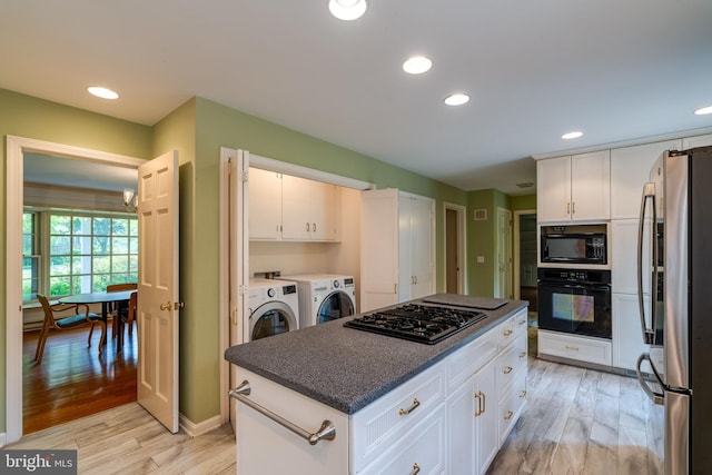 1428 Center Rd, Lancaster, PA 17603 - kitchen with black appliances, washer and clothes dryer, light wood-style flooring, dark countertops, and white cabinetry