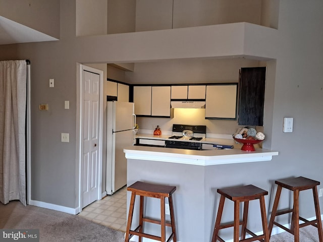 1310W Sheridan Pl Unit 301, Bel Air, MD 21015 - kitchen with freestanding refrigerator, under cabinet range hood, range with gas cooktop, light countertops, and a kitchen bar