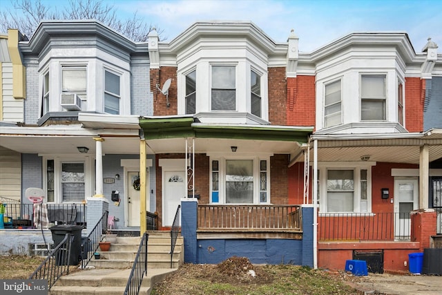 townhome / multi-family property with brick siding and a porch