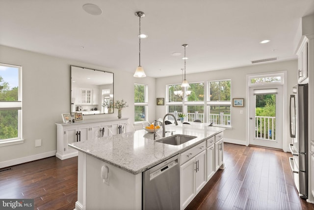 kitchen featuring stainless steel appliances, a sink, plenty of natural light, and dark wood finished floors