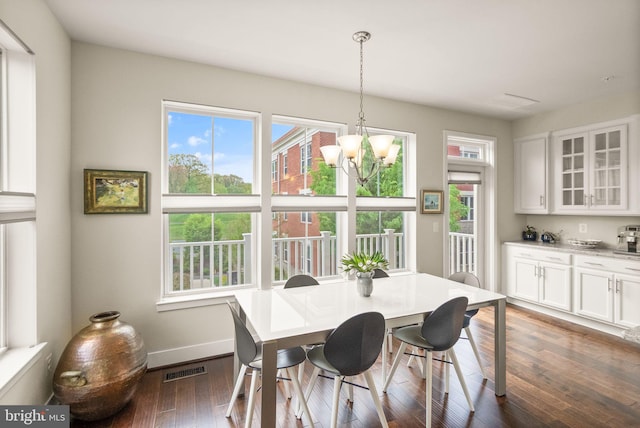 dining area featuring dark wood finished floors, a wealth of natural light, an inviting chandelier, and baseboards