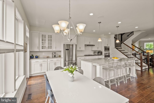 kitchen with visible vents, appliances with stainless steel finishes, dark wood-style floors, and under cabinet range hood