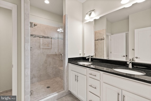 full bathroom with tile patterned floors, a sink, double vanity, and a stall shower