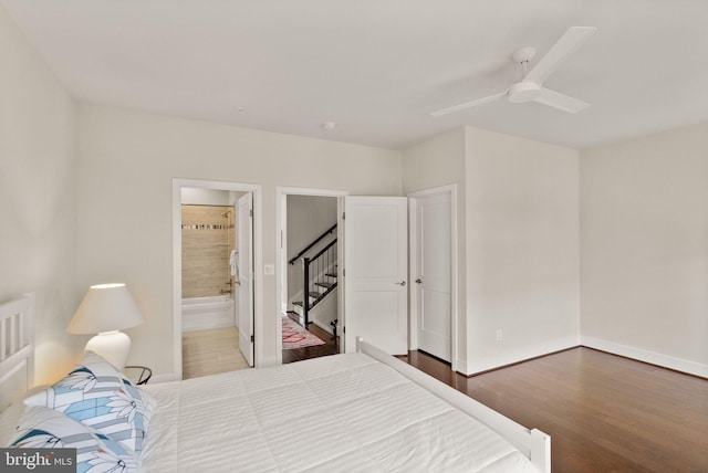 bedroom featuring ensuite bath, baseboards, a ceiling fan, and wood finished floors
