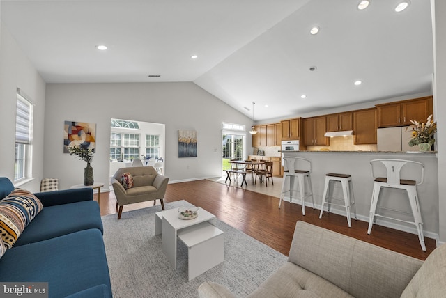 living area featuring wood finished floors, baseboards, lofted ceiling, and recessed lighting