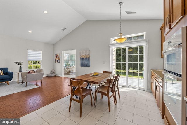 dining room featuring visible vents, baseboards, high vaulted ceiling, and light tile patterned floors