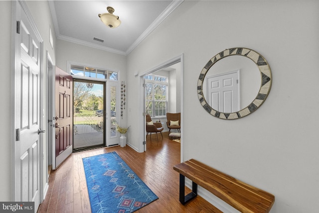 foyer entrance featuring visible vents, baseboards, hardwood / wood-style floors, and crown molding