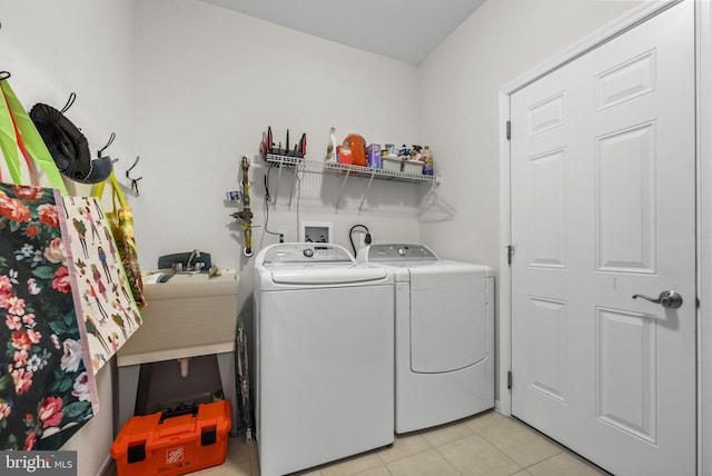 washroom featuring light tile patterned floors, separate washer and dryer, laundry area, and a sink