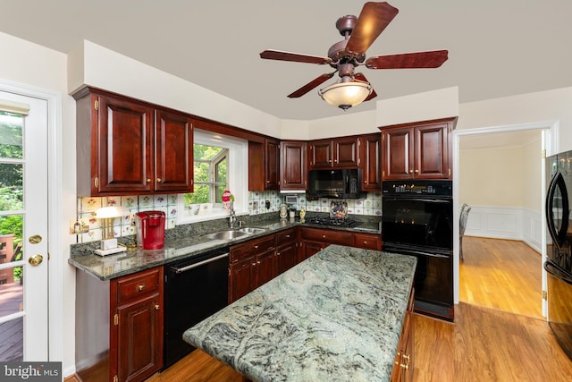 kitchen with black appliances, dark brown cabinets, ceiling fan, light wood-style floors, and a sink