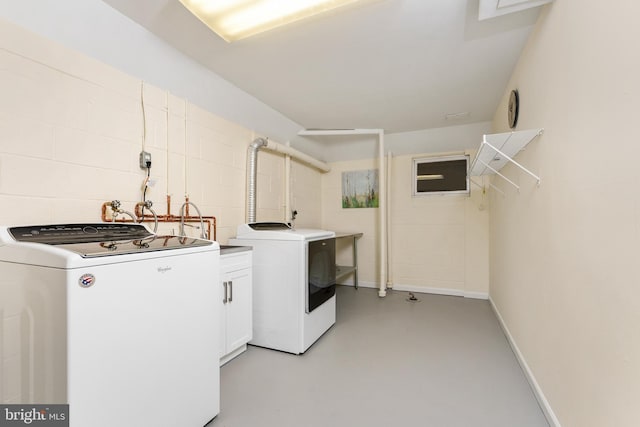 washroom with separate washer and dryer, cabinet space, and baseboards