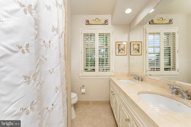 full bath with tile patterned flooring, toilet, double vanity, and baseboards
