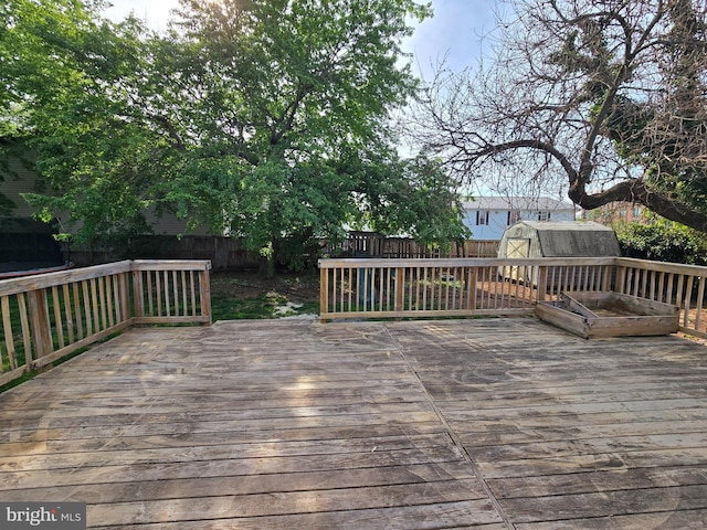 wooden terrace with a storage shed, an outbuilding, and a fenced backyard