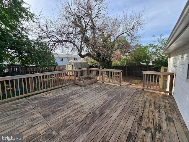 wooden deck featuring a storage unit, an outdoor structure, and a fenced backyard