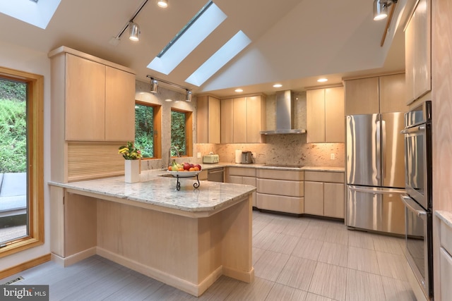 1023 Fairdell Dr, Hummelstown, PA 17036 - kitchen with a skylight, stainless steel appliances, wall chimney exhaust hood, light brown cabinets, and vaulted ceiling