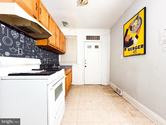 kitchen featuring backsplash, gas range gas stove, under cabinet range hood, brown cabinets, and a sink