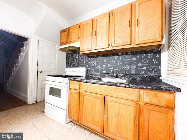 kitchen featuring a sink, white gas range, dark stone counters, and under cabinet range hood